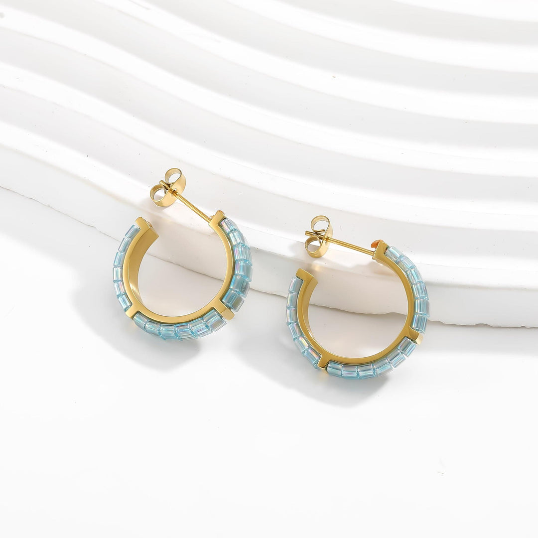 Gold hoop earrings with blue beads on a white background