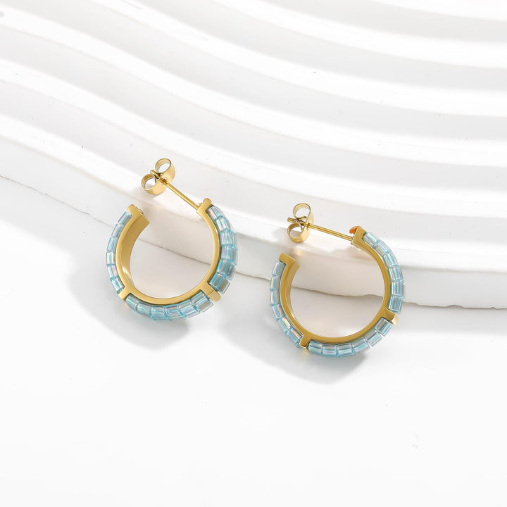 Gold hoop earrings with blue beads on a white background